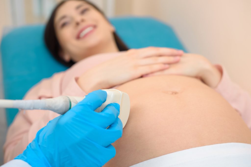 close-up shot of obstetrician gynecologist making ultrasound examination for pregnant woman